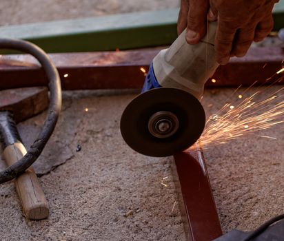 Metal sawing with hand grinder. Sparks while grinding iron.