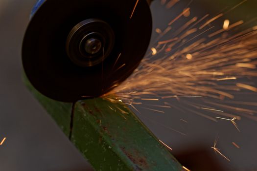 Metal sawing with hand grinder. Sparks while grinding iron.