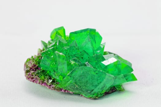 Close up picture about a crystal with emerald color on white background (green crystal)