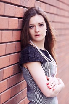 Beautiful girl in black and white dress against a brick wall