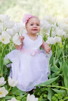 Little girl in an elegant dress to stand near blossoming tulips