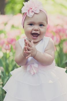 Little girl in an elegant dress to stand near blossoming tulips