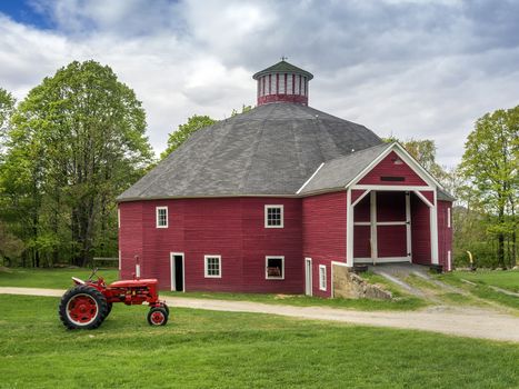 Red New England barn with vintage tractor in foreground
