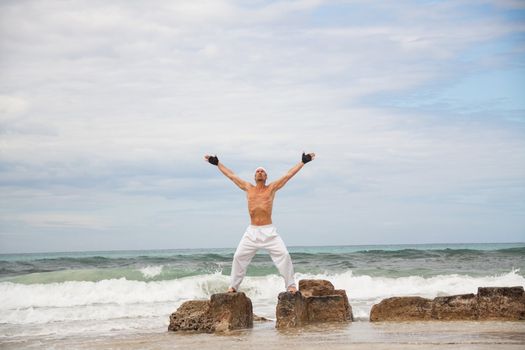 healthy man doing pilates yoga meditation on beach summer freedom