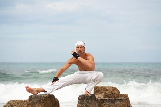 healthy man doing pilates yoga meditation on beach summer freedom