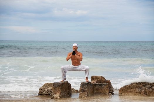 healthy man doing pilates yoga meditation on beach summer freedom