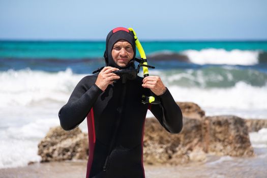 male diver with diving suit snorkel mask fins on the beach in Summer