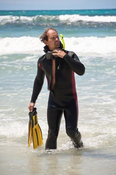 male diver with diving suit snorkel mask fins on the beach in Summer