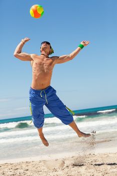 attractive young man playing volleyball on the beach summertime 