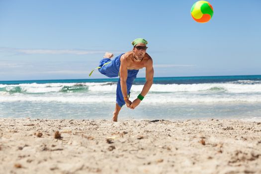 attractive young man playing volleyball on the beach summertime 