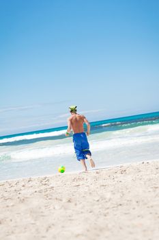 attractive young man playing volleyball on the beach summertime 
