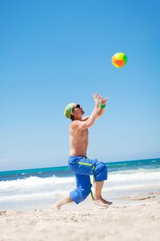 attractive young man playing volleyball on the beach summertime 
