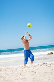 attractive young man playing volleyball on the beach summertime 