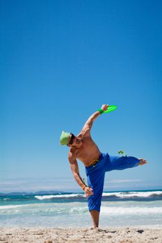 attractive man playing frisby on beach in summer sport fitness jump