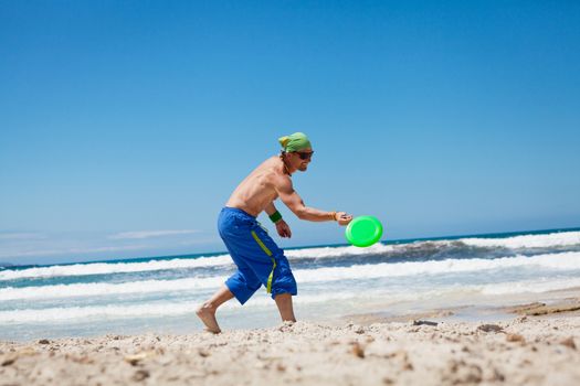 attractive man playing frisby on beach in summer sport fitness jump
