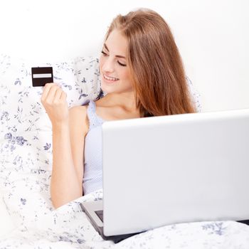 girl sitting in bed and shopping online with credit card onlineshop ecommerce