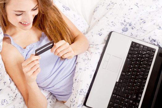 girl sitting in bed and shopping online with credit card onlineshop ecommerce