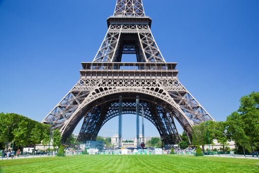 Eiffel Tower lower part seen from Champ de Mars at a sunny summer day, Paris, France