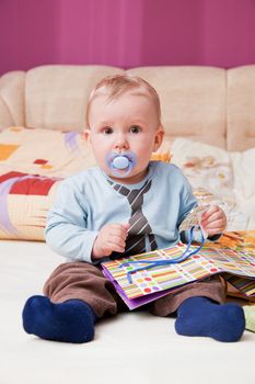 Young baby boy with a dummy in his mouth looking at the camera