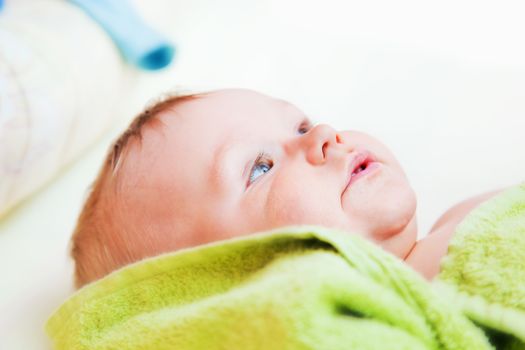 A baby waiting for changing his napkin, lying on bed