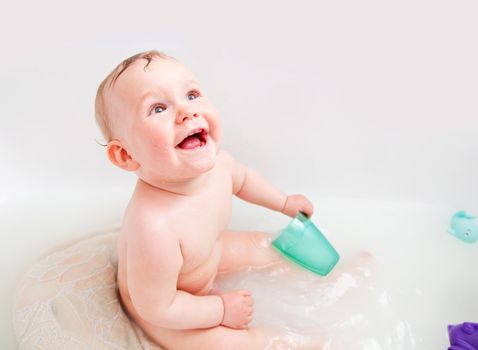 Cute happy baby laughing in a bathroom. This little boy is having on of his first baths