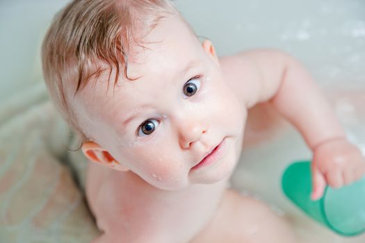Cute happy baby in a bathroom. This little boy is having one of his first baths