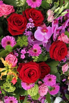 red and pink roses, pink orchids and gerberas in a floral arrangement