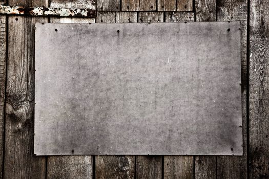 Old grunge plywood board on a wooden wall. Scratched and rusty. Good for background, texture.