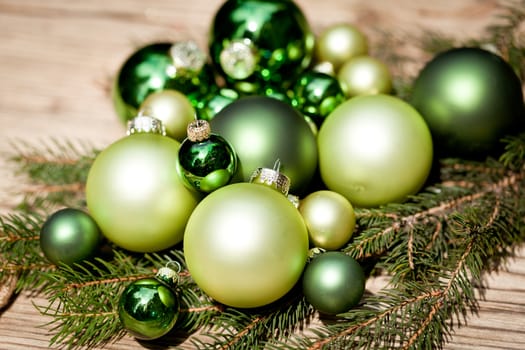 shiny green christmas baubles closeup macro and tree on wooden background