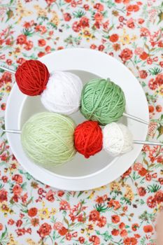 A lot of bright balls of knitting on the background of a red flower