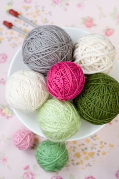 A lot of bright balls of knitting on the background of a pink flower