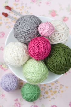 A lot of bright balls of knitting on the background of a pink flower