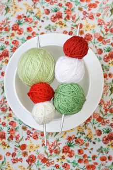 A lot of bright balls of knitting on the background of a red flower
