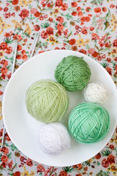 A lot of bright balls of knitting on the background of a red flower