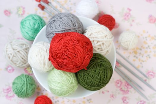 A lot of bright balls of knitting on the background of a pink flower