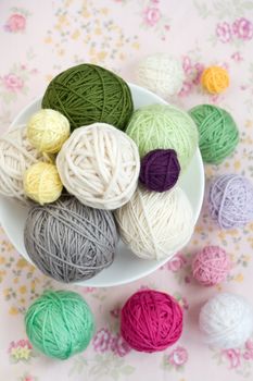 A lot of bright balls of knitting on the background of a pink flower