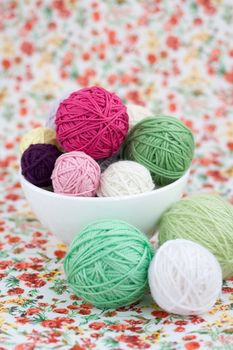 A lot of bright balls of knitting on the background of a red flower