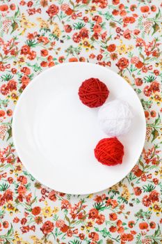 White plate, the spokes, red and white ball on the background of a red flower