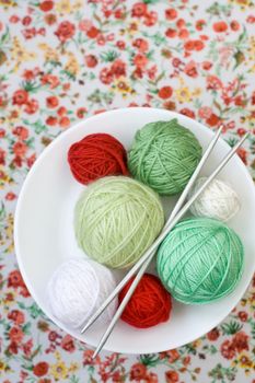 A lot of bright balls of knitting on the background of a red flower