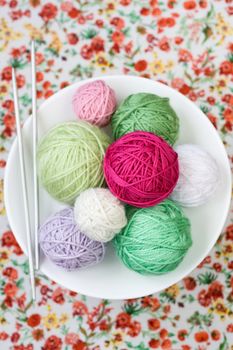 A lot of bright balls of knitting on the background of a red flower