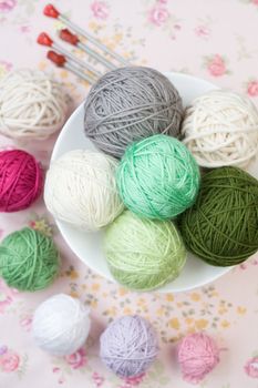 A lot of bright balls of knitting on the background of a pink flower