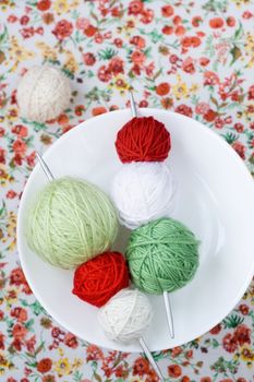 A lot of bright balls of knitting on the background of a red flower