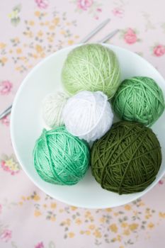 A lot of bright balls of knitting on the background of a pink flower