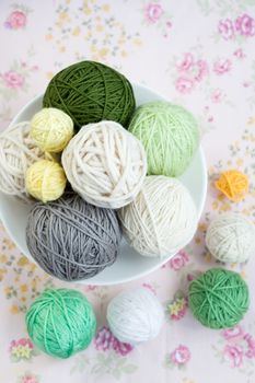 A lot of bright balls of knitting on the background of a pink flower