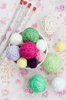 A lot of bright balls of knitting on the background of a pink flower