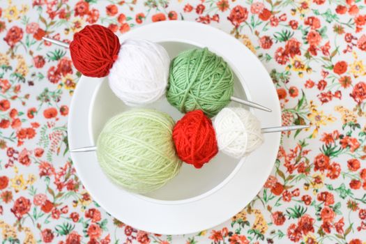 A lot of bright balls of knitting on the background of a red flower