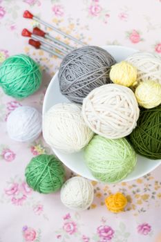 A lot of bright balls of knitting on the background of a pink flower
