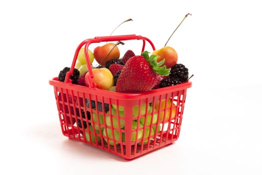 A red shopping basket full of oversized fruits and berries.