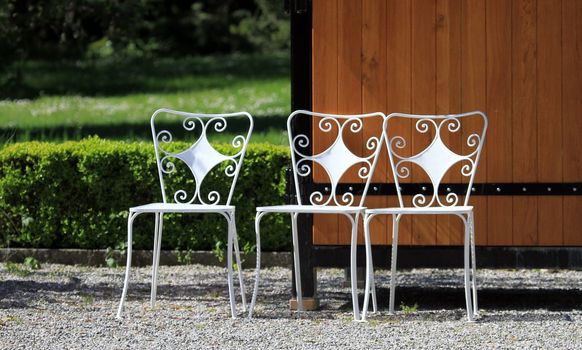 Three white iron chair in garden with green grass