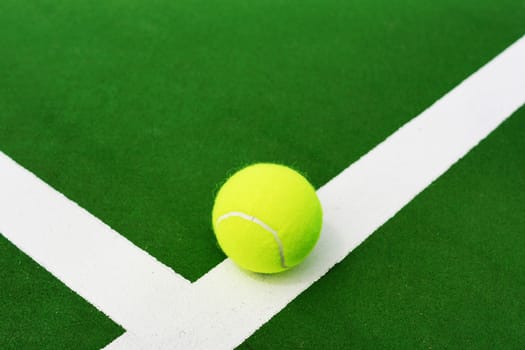Tennis ball on white line of hard court